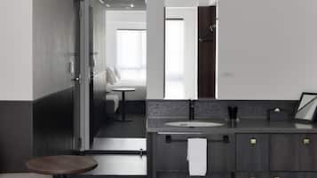 A modern bathroom with a dark wood vanity, a round sink, and a mirror.