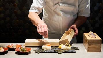 A chef preparing sushi with wooden boxes and plates on a table.