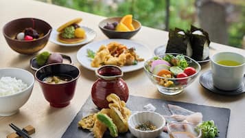 Diverses parelles de plats japonesos sobre una taula de fusta, com sushi, tempura i un bol d'arròs.