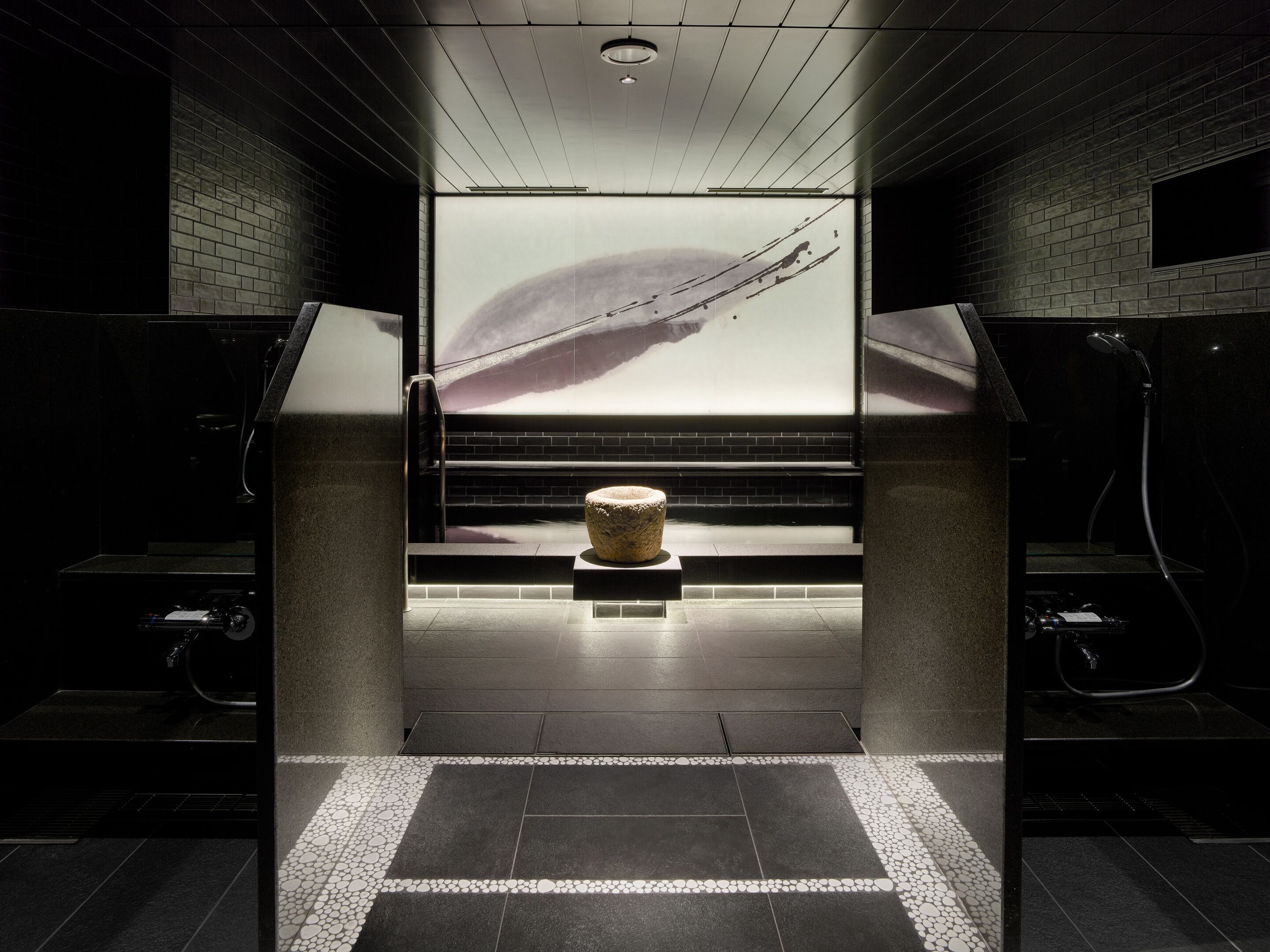 A modern bathroom with a large mirror, a stone sculpture, and a view of a bridge.