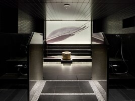 A modern bathroom with a large mirror, a stone sculpture, and a view of a bridge.