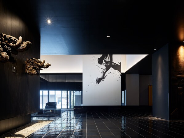 Un hall d’entrée spacieux avec un sol mouillé, une grande fresque murale et des éléments de décoration traditionnels.
