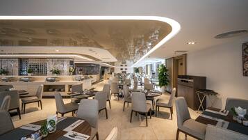 Un restaurante moderno con barra central, varias zonas de comedor y una variedad de disposiciones de asientos.