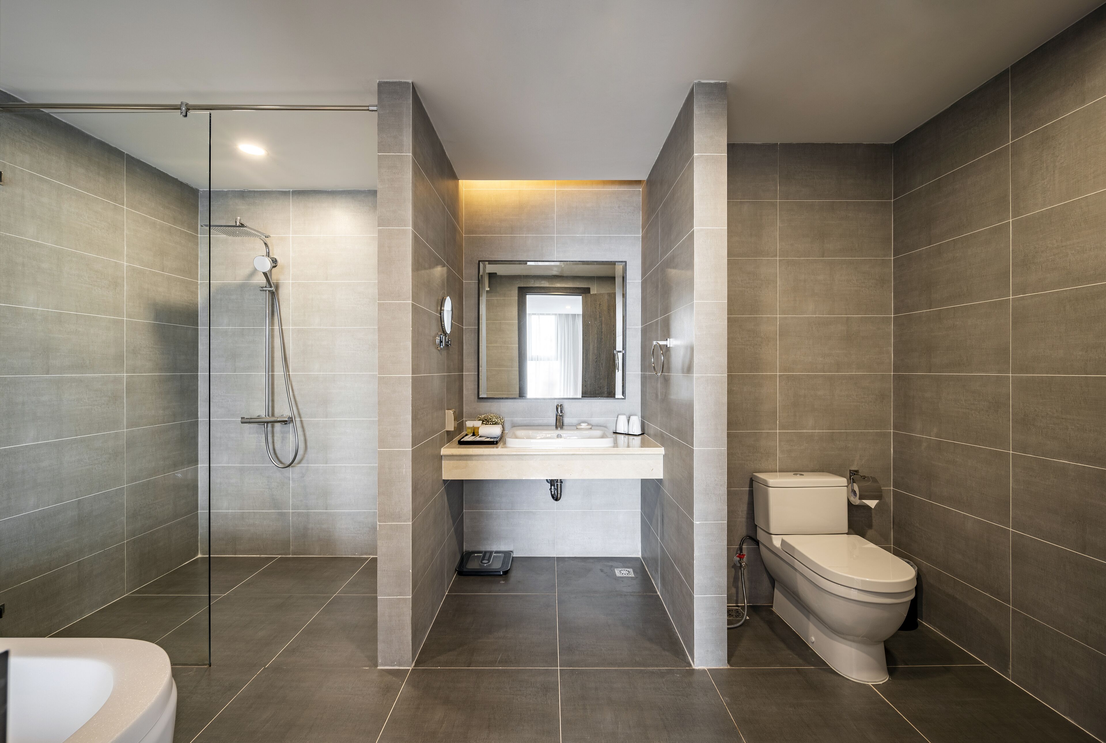 A modern bathroom with a glass-enclosed shower, a sink with a mirror above, and a toilet.