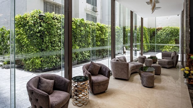 Un interior moderno con luminarias curvas en el techo, ventanas amplias y una zona de estar con sofás y una mesa de centro.
