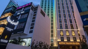 Un hotel moderno con un cartel llamativo de Muong Thanh Sai Gon, que cuenta con una entrada espaciosa y una fachada bien iluminada.