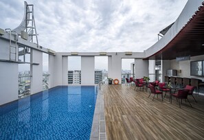 A rooftop pool with a wooden deck and red chairs, overlooking a cityscape. - Muong Thanh Luxury Saigon Hotel (Ho Chi Minh City)