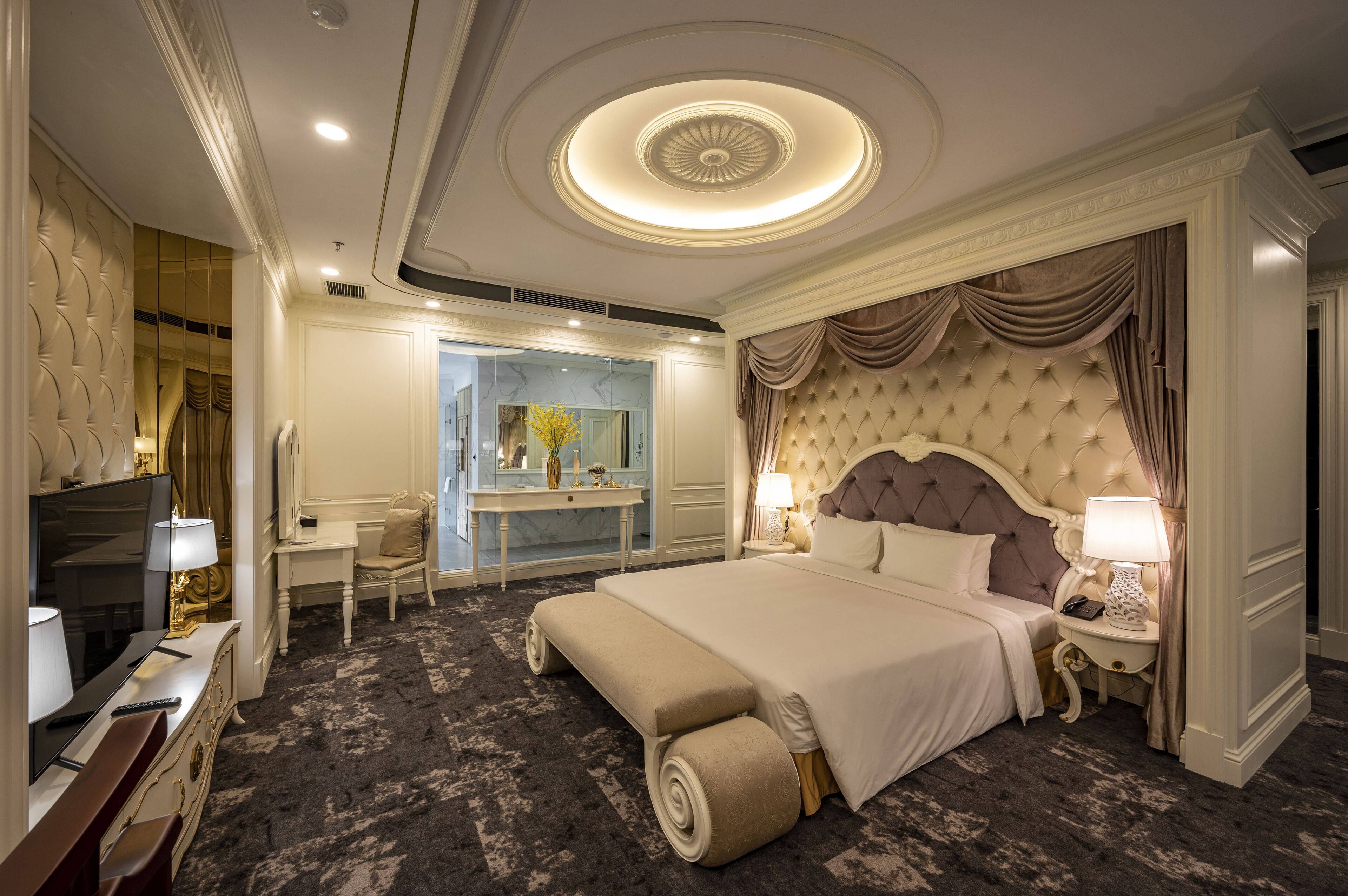Um quarto de hotel luxuoso com uma cama grande, uma toucador com espelho, uma escrivaninha e uma televisão.