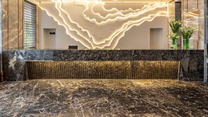 Un área de recepción moderna con suelo de mármol, mostrador de recepción y una lámpara de techo original.