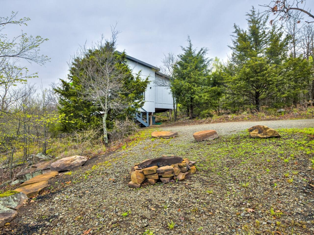 A rustic cabin with a gravel path leading to it, surrounded by trees and rocks.