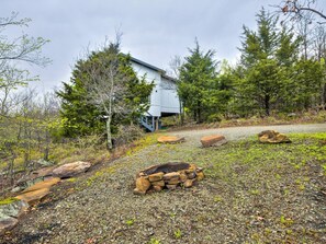 Een rustiek vakantiehuisje met een grindpad er naartoe, omgeven door bomen en rotsen.