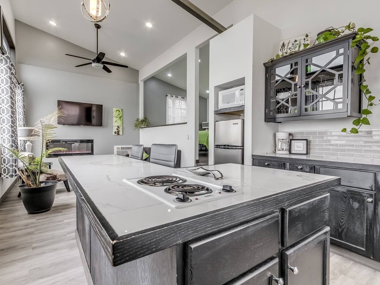 A modern kitchen with a large island, built-in appliances, and a ceiling fan.