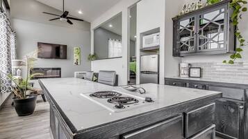 A modern kitchen with a large island, built-in appliances, and a ceiling fan.