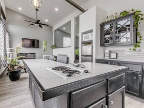 A modern kitchen with a large island, built-in appliances, and a ceiling fan.