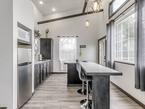 A modern kitchen with stainless steel appliances, a bar area, and a window with a view.