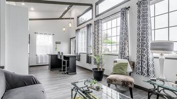 Una sala moderna con un sofá, una mesa de centro de vidrio y un comedor con una silla y una mesa.