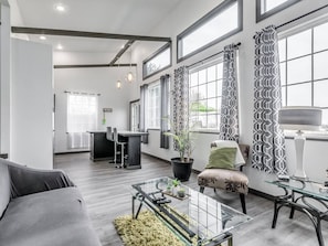 A modern living room with a sofa, a glass coffee table, and a dining area with a chair and a table.