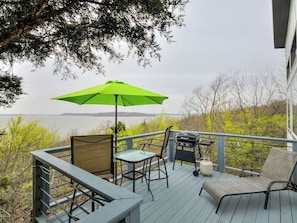 A deck with outdoor furniture, a grill, and a view of a body of water.