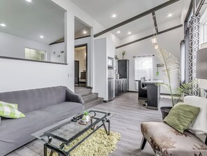 A modern living room with a sofa, coffee table, and a dining area with a chair.