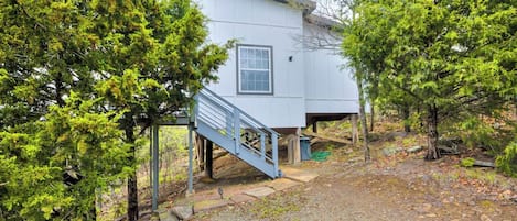 A two-story building with a staircase leading to the entrance, surrounded by trees.
