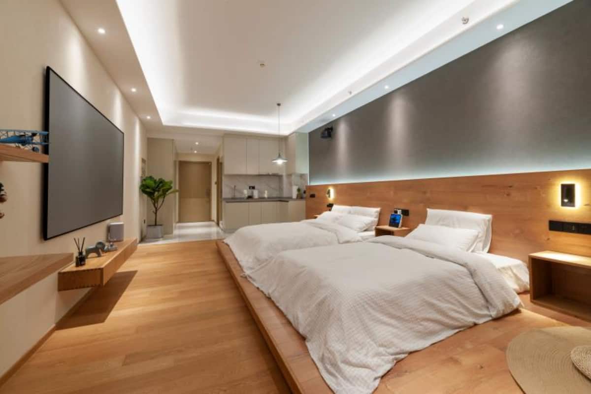 Une chambre moderne avec un grand lit, des tables de chevet, un téléviseur à écran plat et une tête de lit en bois.