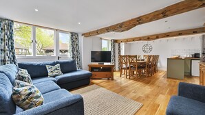 A modern living room with a sofa, TV, dining table, and kitchen area. - Great Higham Barn Complex by Bloom Stays -  sleeps 44 in 13 bedrooms (Sittingbourne)