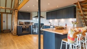 A modern kitchen with dark cabinets, a wooden island, and a built-in oven. - Great Higham Barn Complex by Bloom Stays -  sleeps 44 in 13 bedrooms (Sittingbourne)