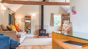 A cozy living room with a sofa, a wooden floor, a fireplace, a bookshelf, and a mirror.
