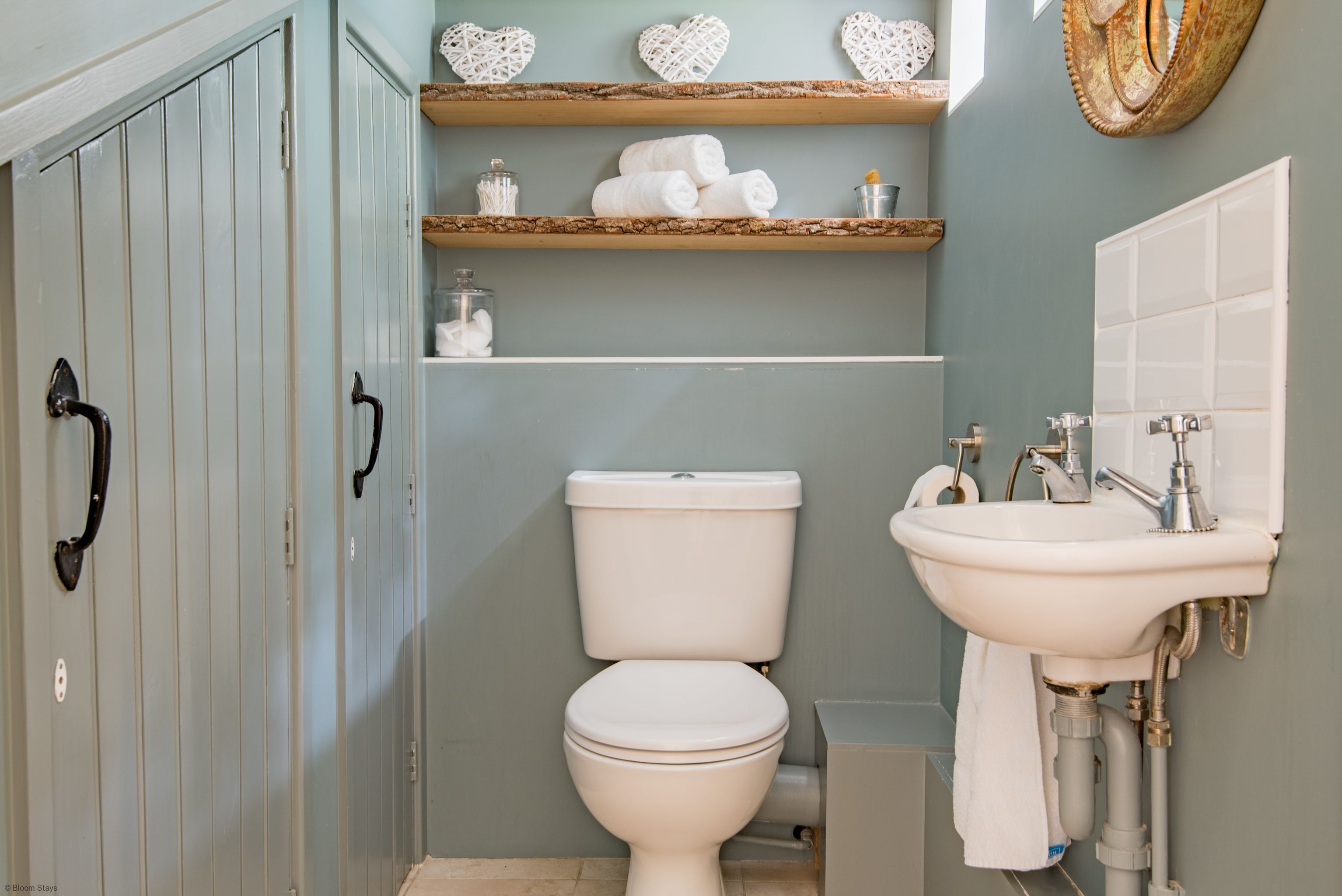 Een badkamer met een toilet, een wastafel en een plank met handdoeken.