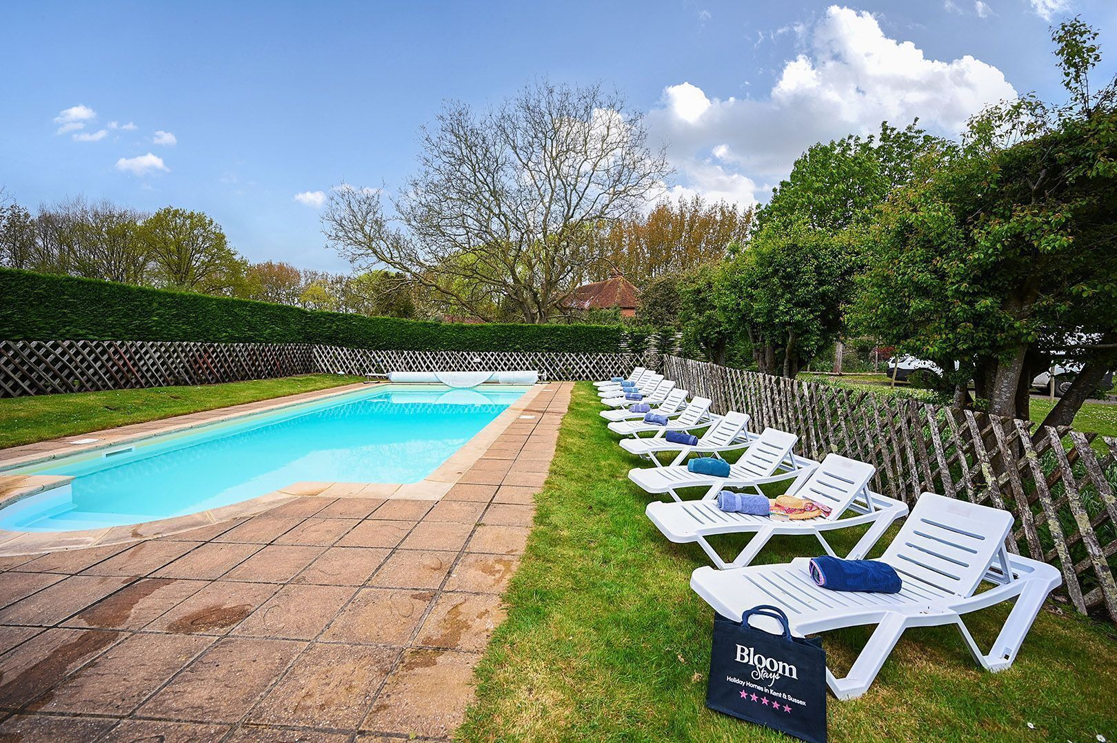 A swimming pool with lounge chairs and a sign for 'Bloom Stays.'