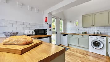 Une cuisine moderne avec un plan de travail en bois, une miche de pain, un four à micro-ondes, un grille-pain et un lave-linge.