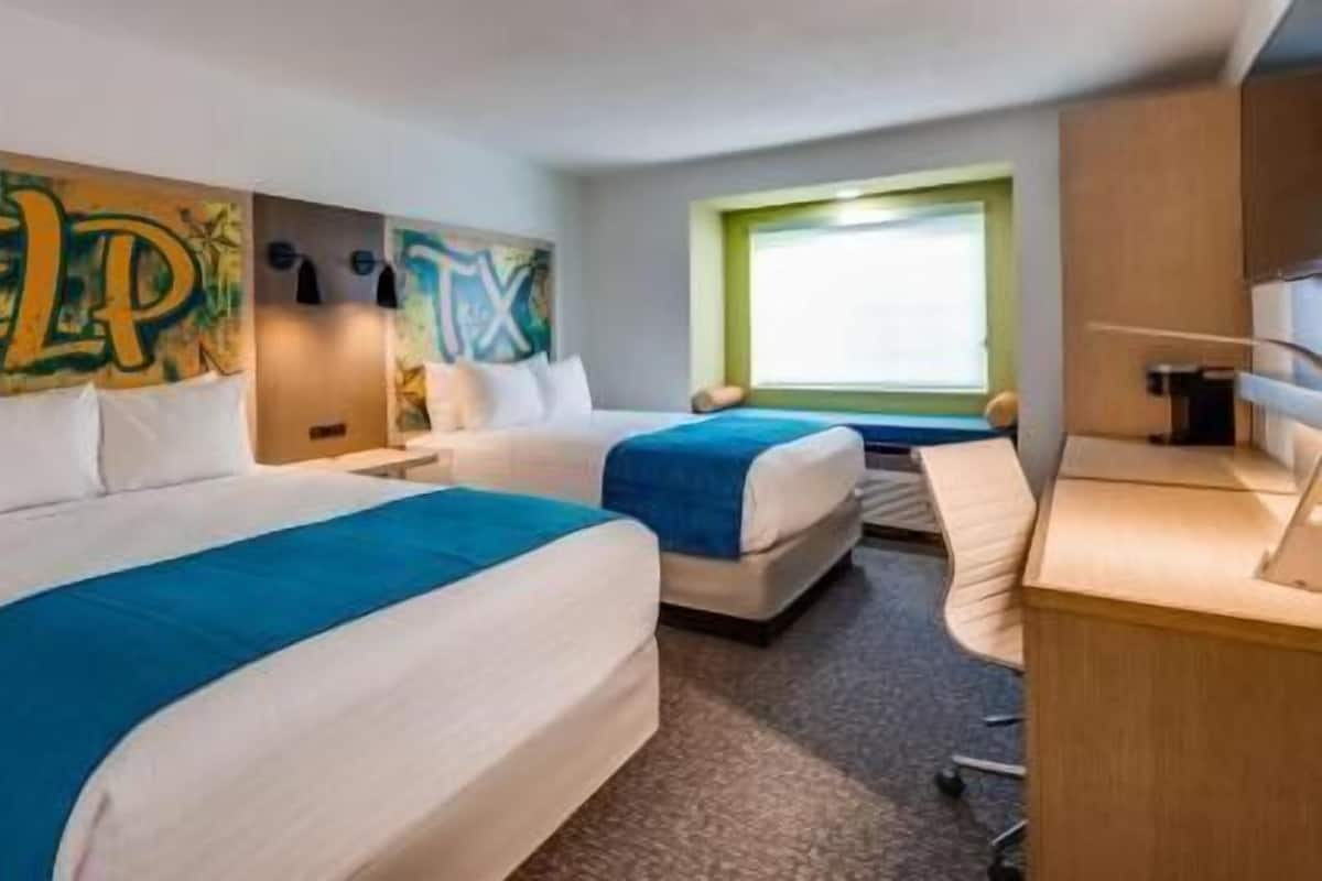 Habitación de hotel con dos camas, un escritorio y una ventana.