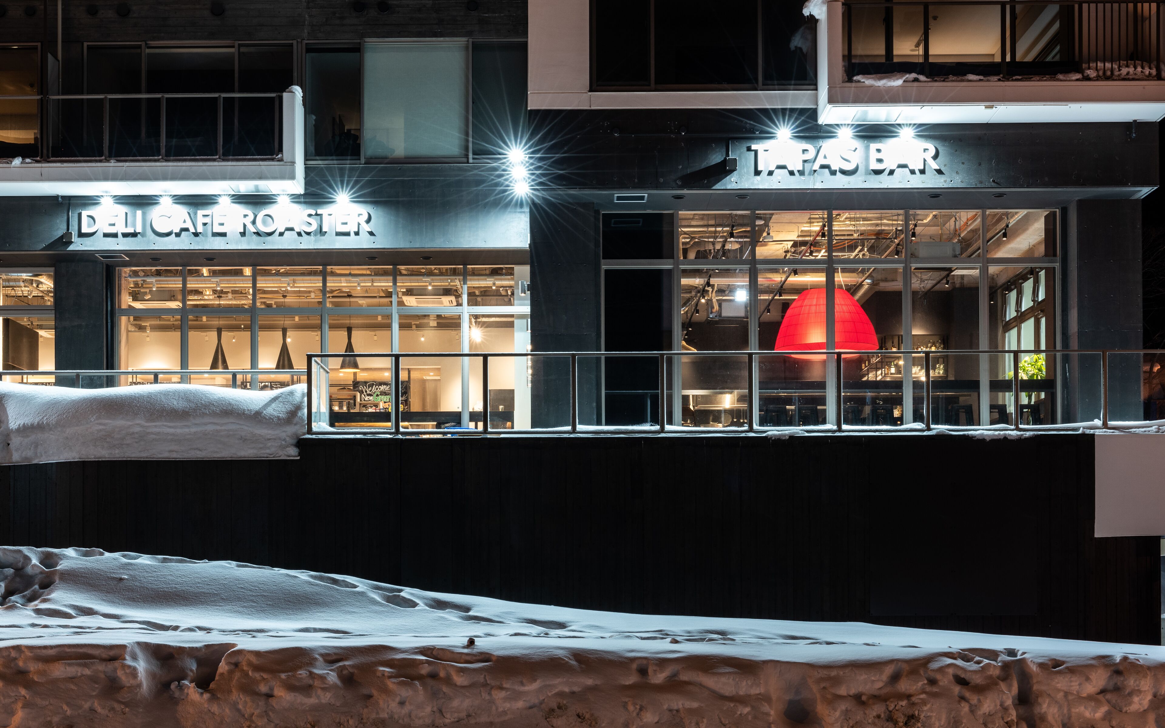 A building with a cafe named 'DELICA ROASTER' and a bar named 'TAPAS BAR'.