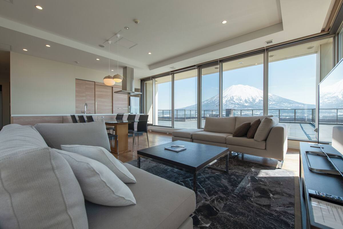 Un salón moderno con sofá, una mesa de centro y vista a la montaña.