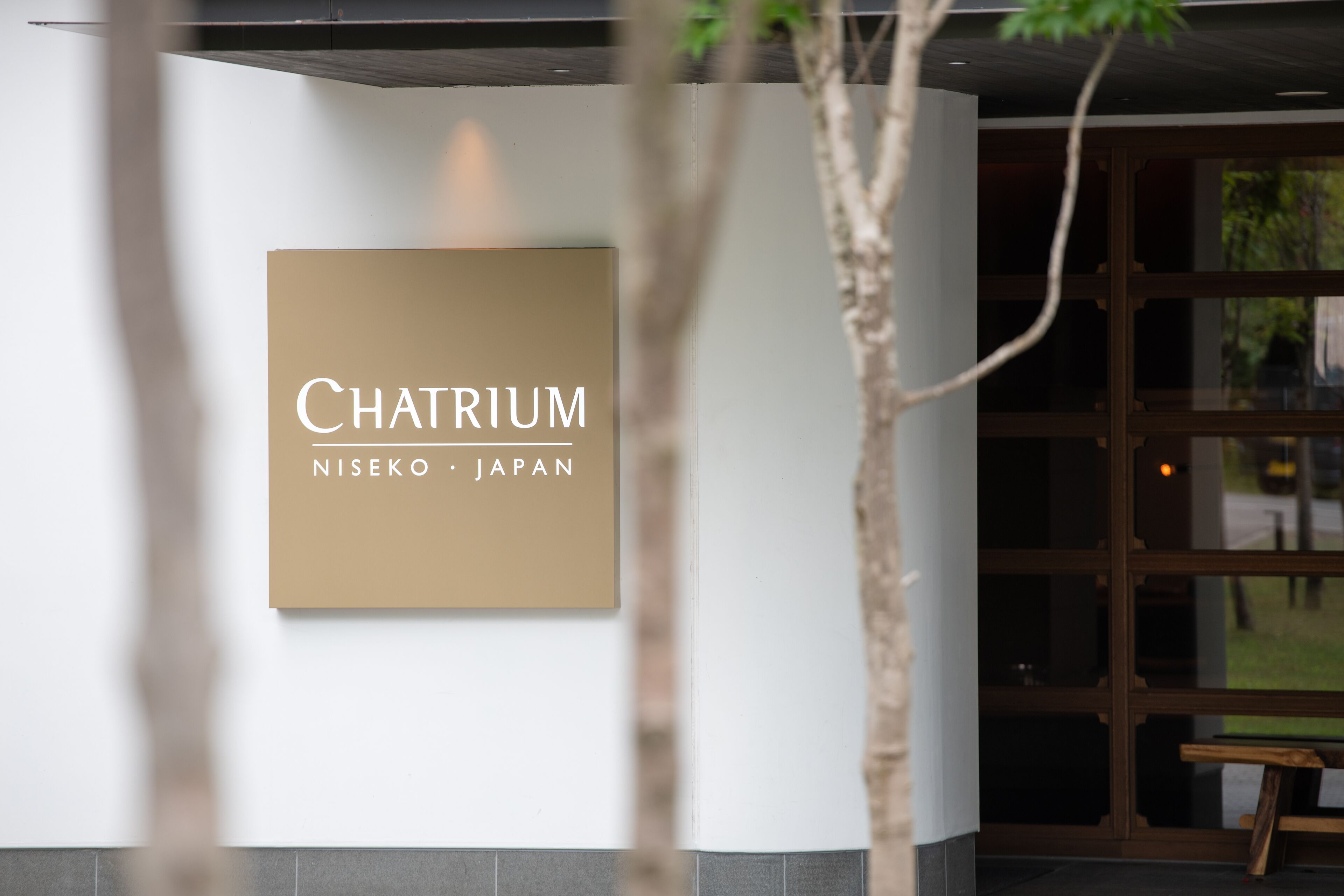 Ein Schild mit der Aufschrift 'Chatrium Niseko Japan' an einer weißen Wand.