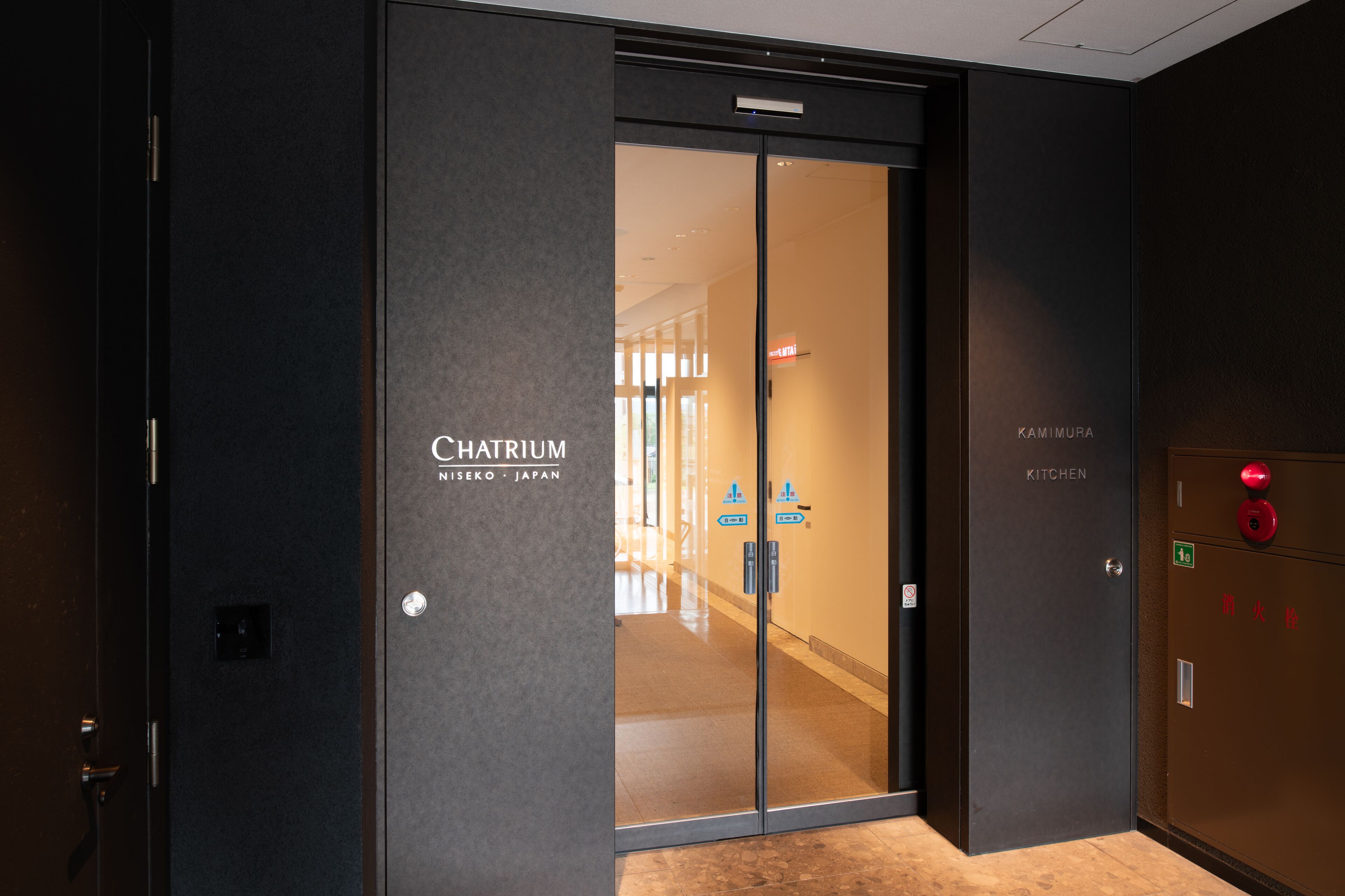 Entrada de hotel com porta de vidro identificada como "Chattrium Nishi-ko Japan".