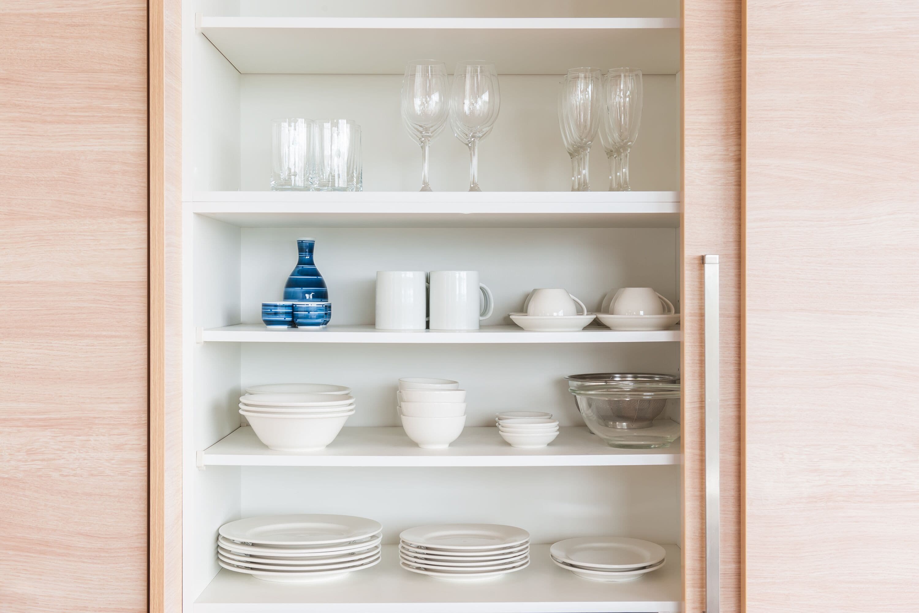 A white shelving unit with various glassware, bowls, and plates.