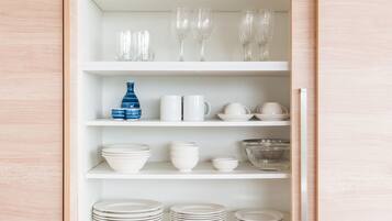 A white shelving unit with various glassware, bowls, and plates.