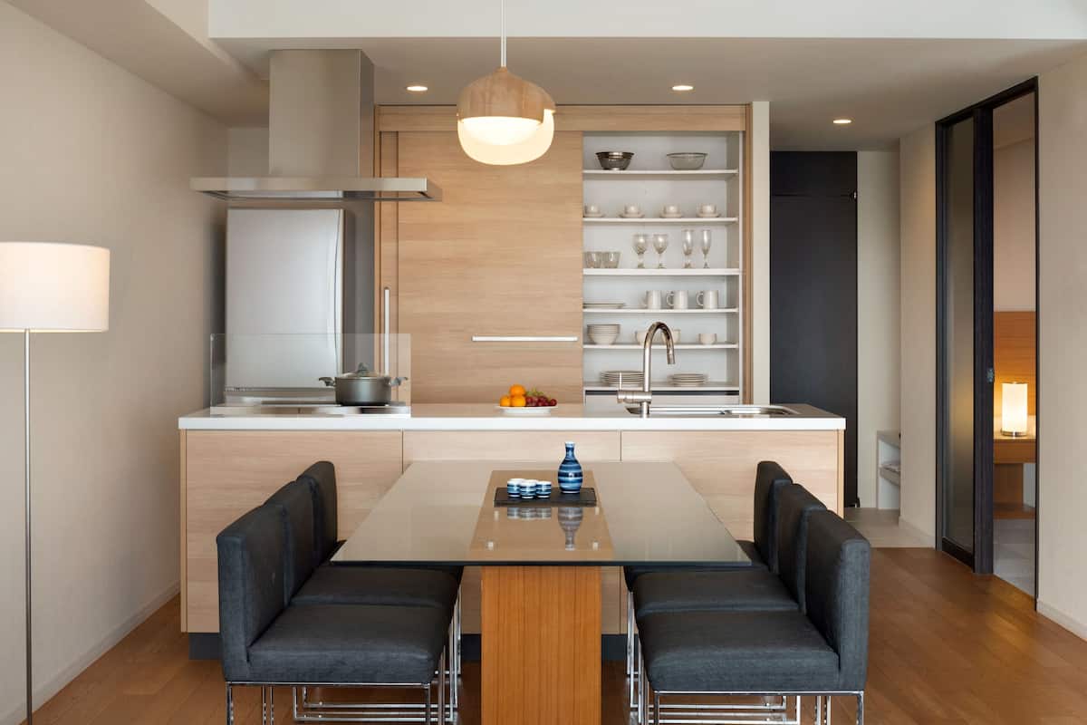 Una cocina moderna con una isla central, estanterías empotradas y un comedor con dos sillas.