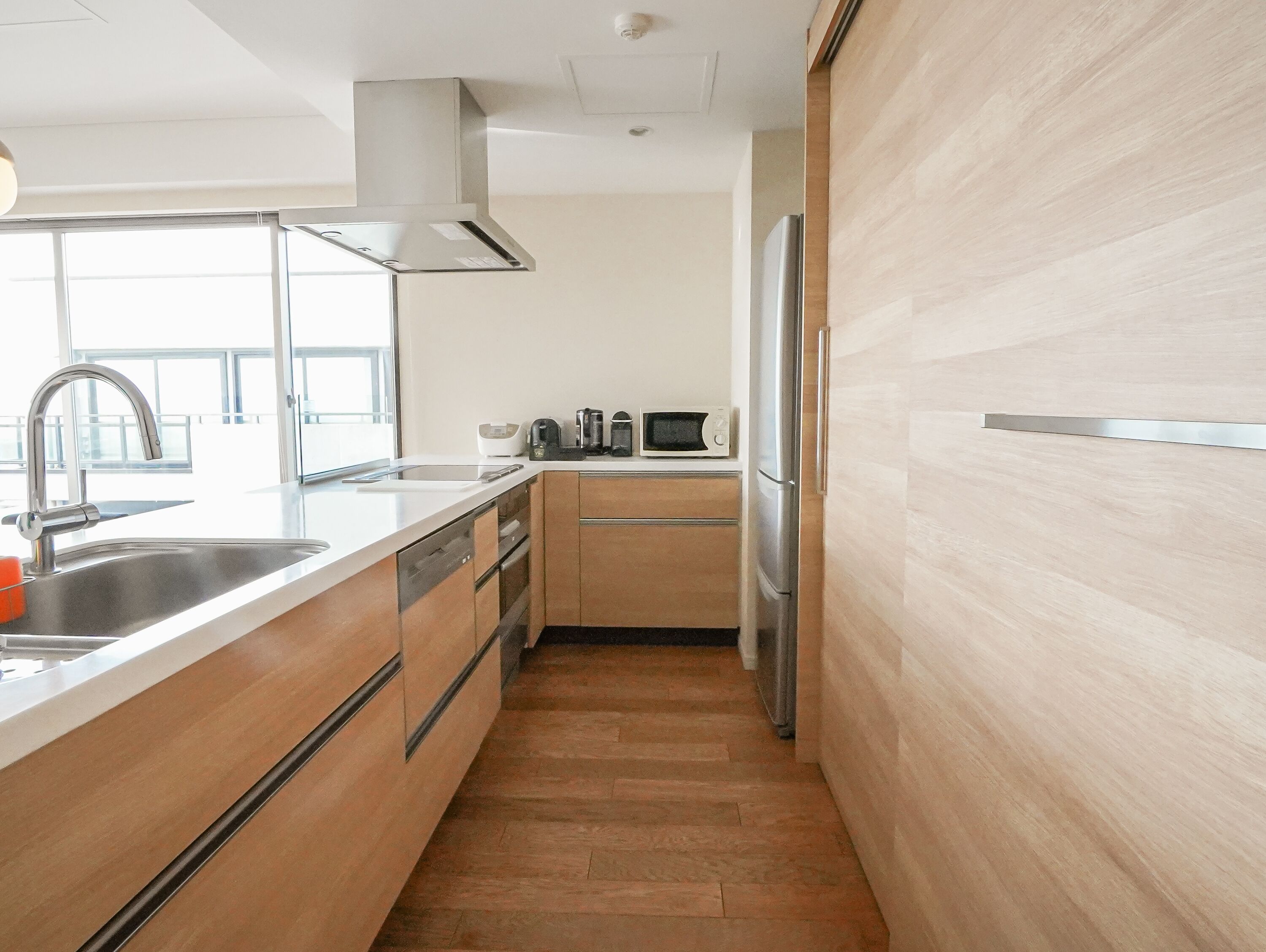 Una cocina moderna con un lavamanos de acero inoxidable, un microondas y un refrigerador.
