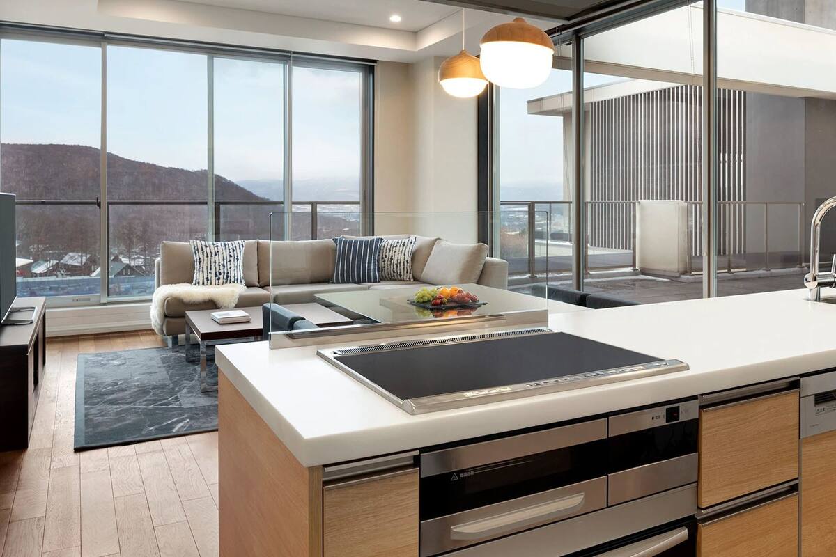 Una cocina moderna con una isla grande, electrodomésticos de acero inoxidable y vistas a la ciudad.