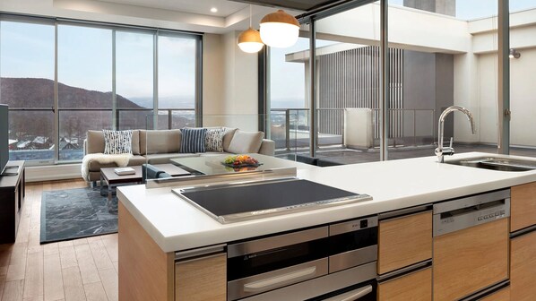 Uma cozinha moderna com uma ilha grande, eletrodomésticos de aço inoxidável e vista para a cidade.