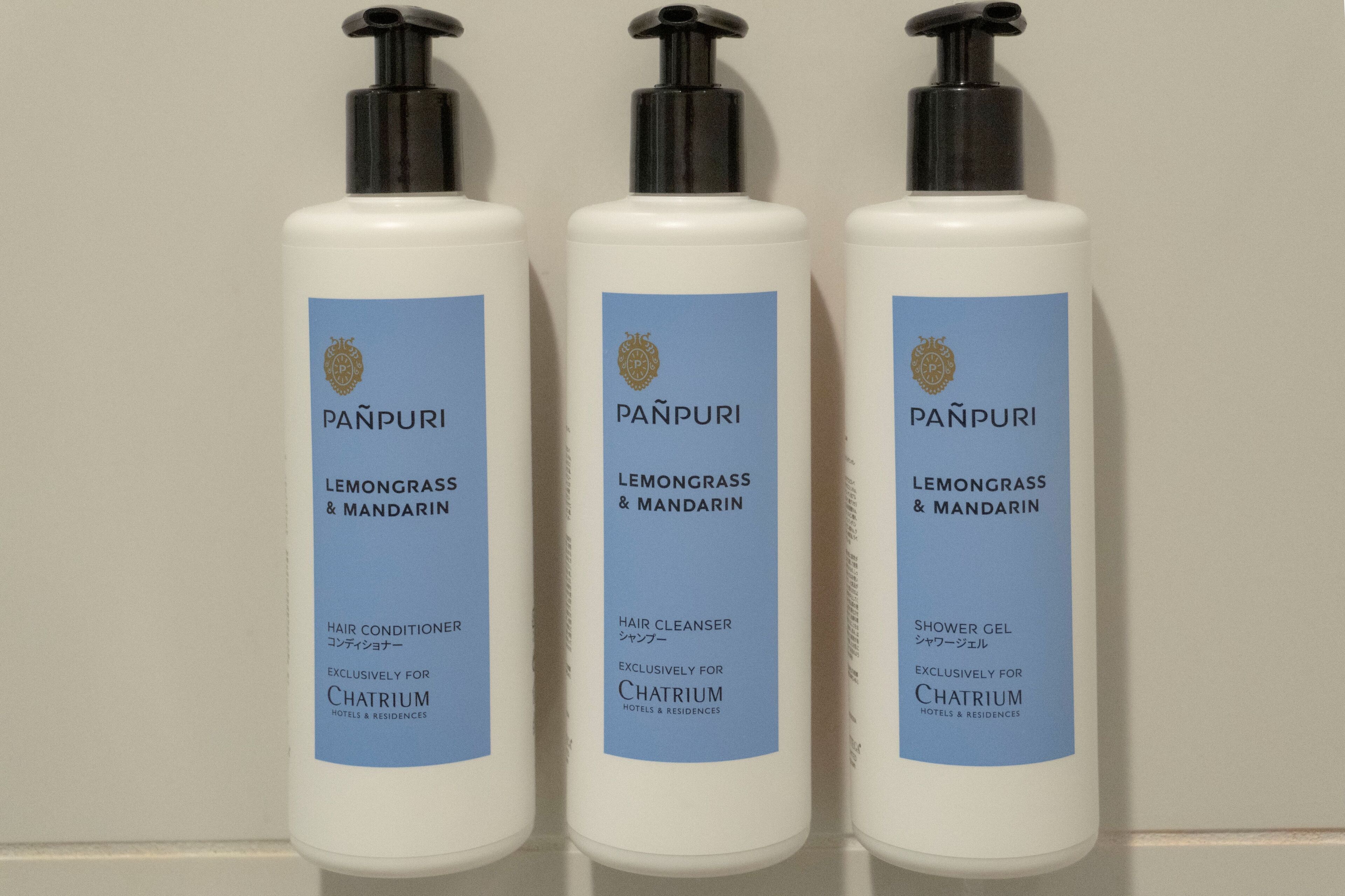 Três frascos de produtos para cabelo Panpuri identificados para hotéis e residências.