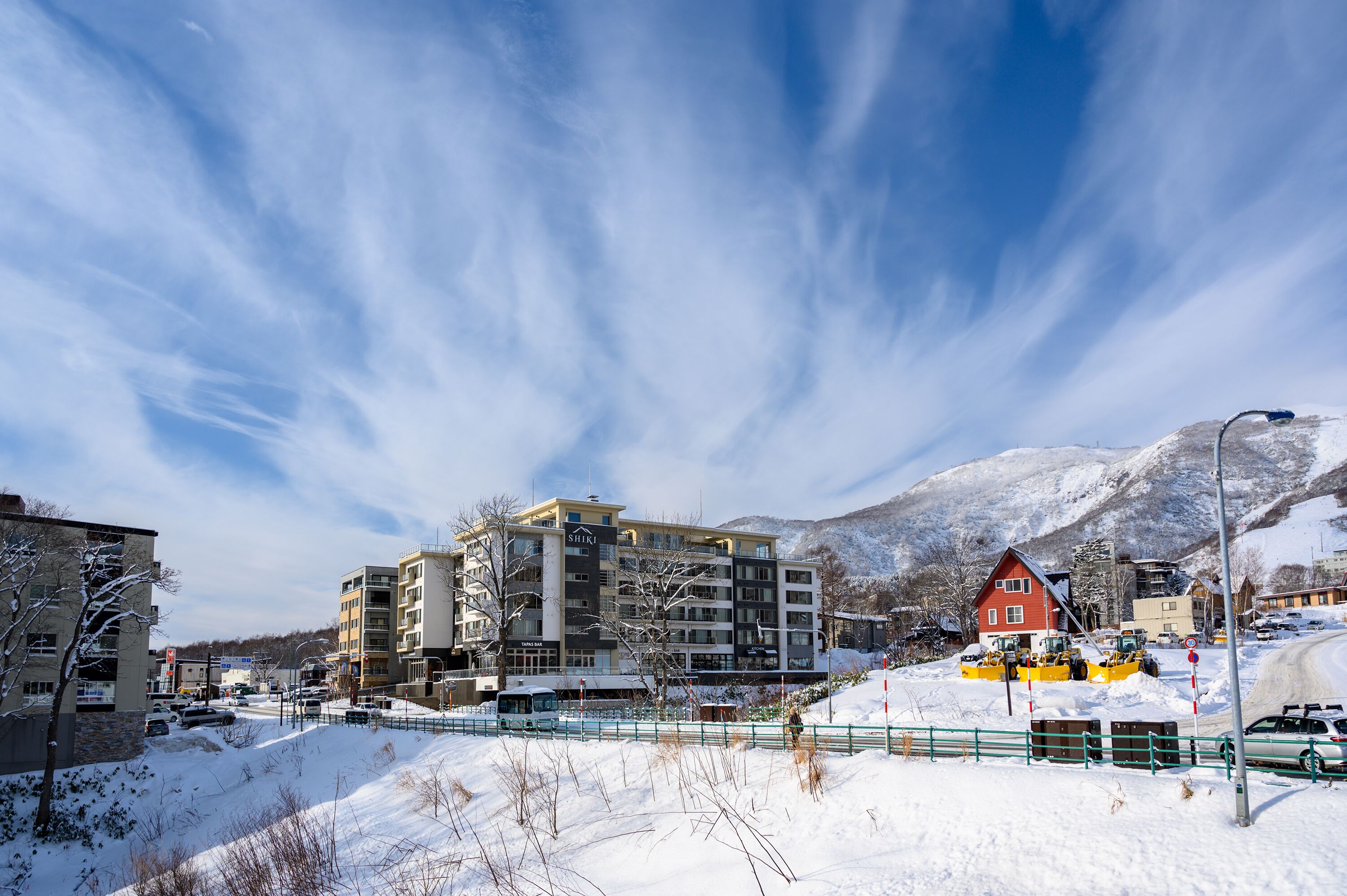 A hotel with multiple floors, a red building in the background, and snow-covered surroundings.