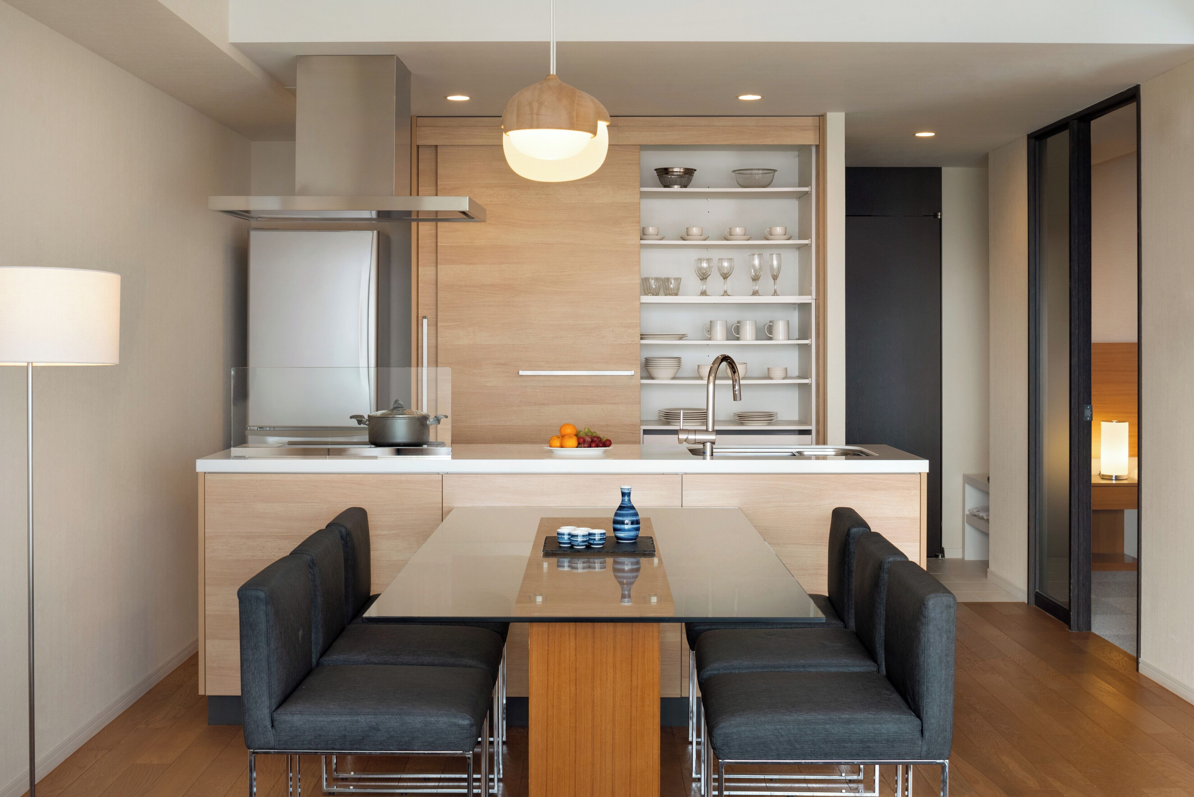 A modern kitchen with a central island, built-in shelves, and a dining area with a table and chairs.