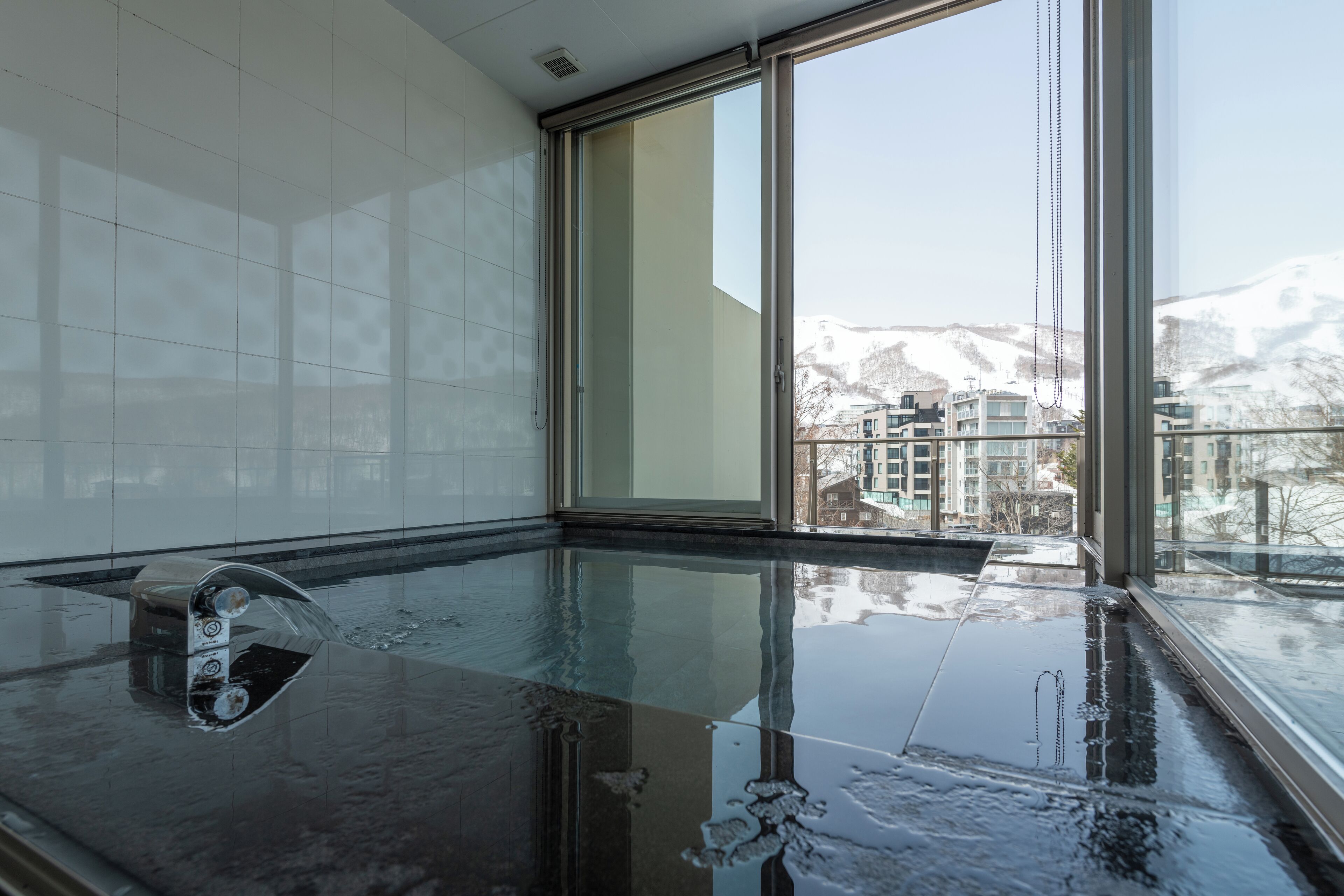 Une piscine intérieure moderne offrant une vue dégagée sur les montagnes enneigées grâce à de grandes fenêtres.