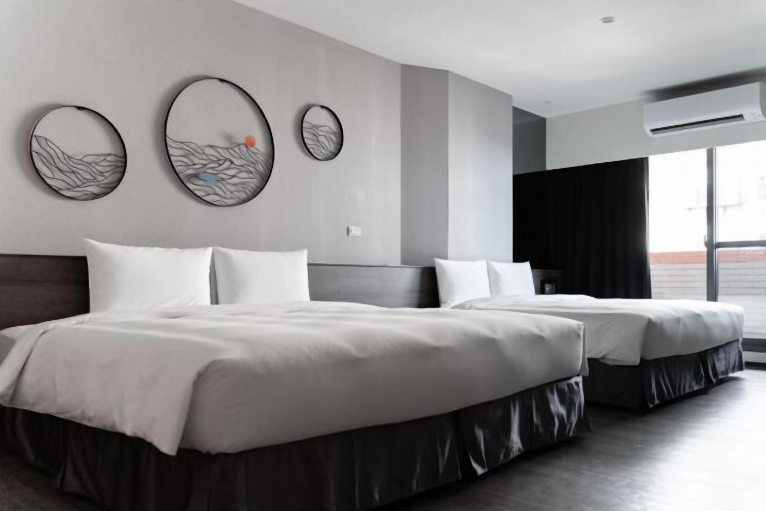 Une chambre d’hôtel avec deux lits, une grande fenêtre et des œuvres d’art murales.