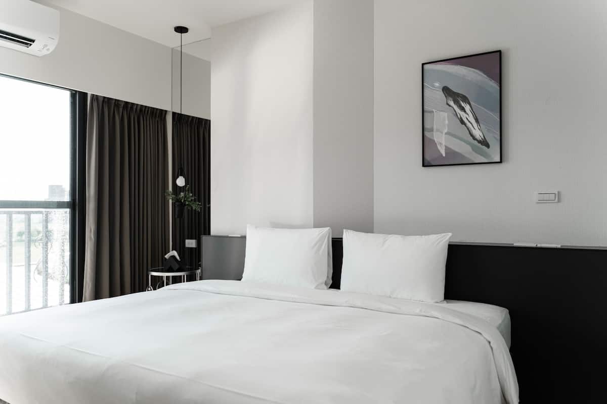 Una habitación de hotel moderna con una cama grande, un escritorio y vistas de la ciudad a través del ventanal.