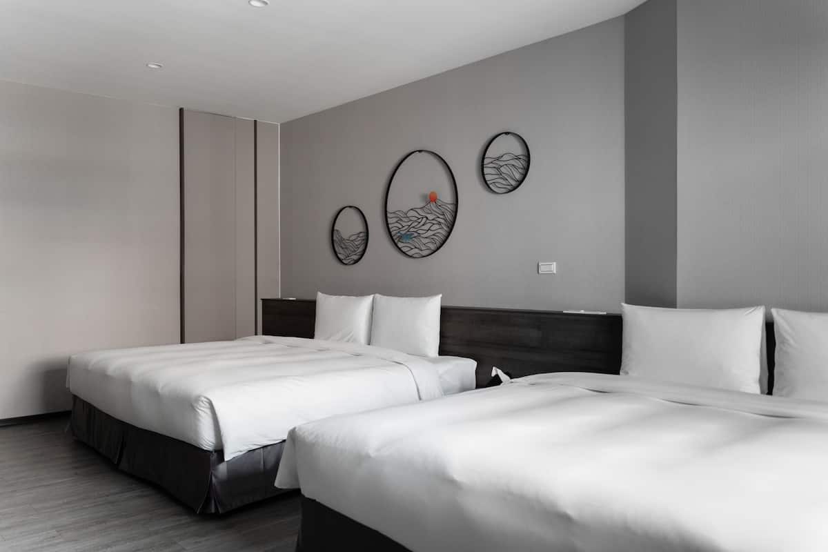 Una habitación de hotel con dos camas, cabecero de madera y una obra de arte colgada en la pared.