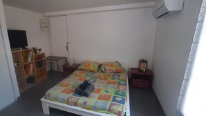 A bedroom with a bed, a TV, a wardrobe, a bedside table, and a nightstand.